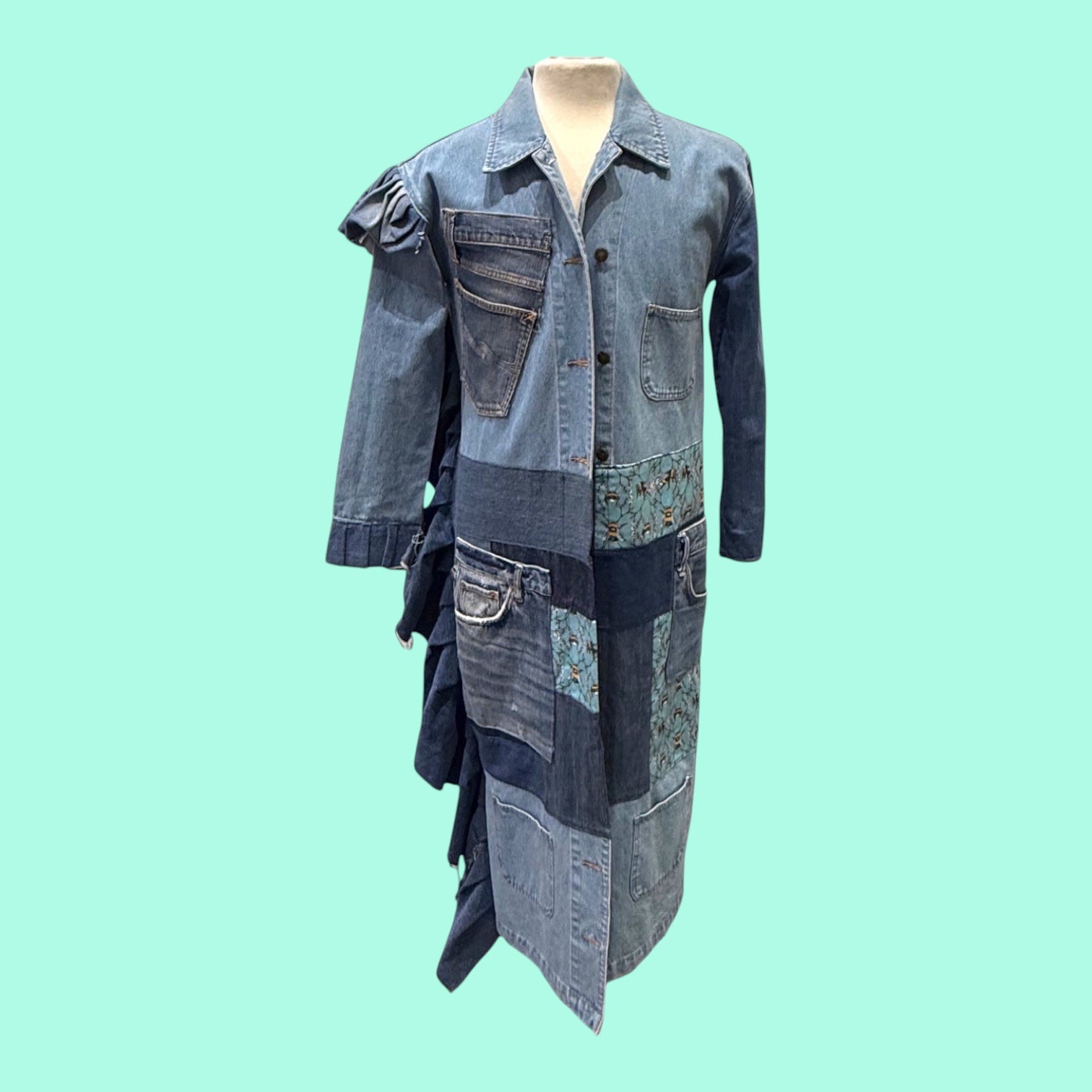 Blue Greenie Malcolm X denim patchwork coat with ruffled side detail and mixed wash denim panels on a mannequin