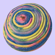 Blue Greenie eggshell white beret featuring concentric pastel tie-dye t-shirt fabric strips in a spiral design.