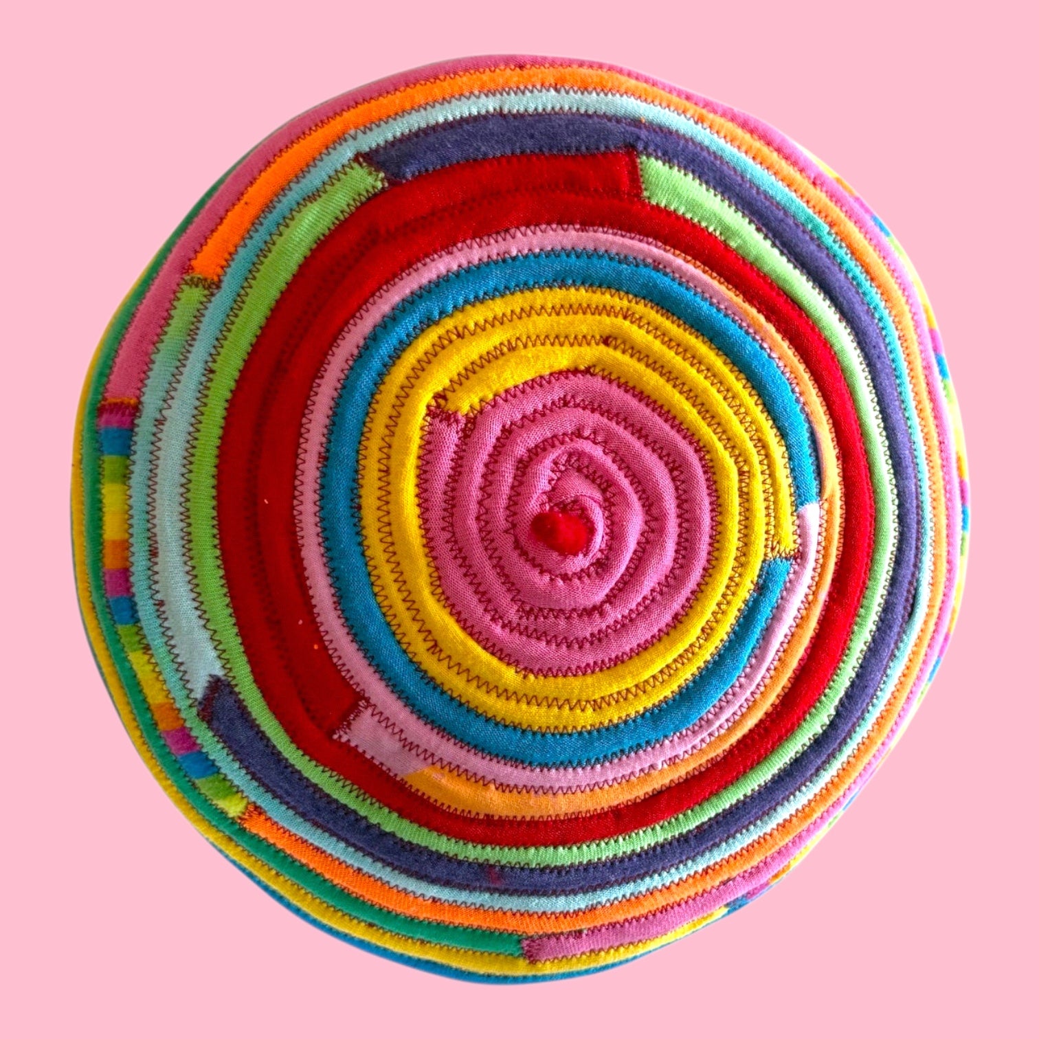 Blue Greenie red wool beret featuring a vibrant spiral pattern made from colorful sewn t-shirt fabric strips.