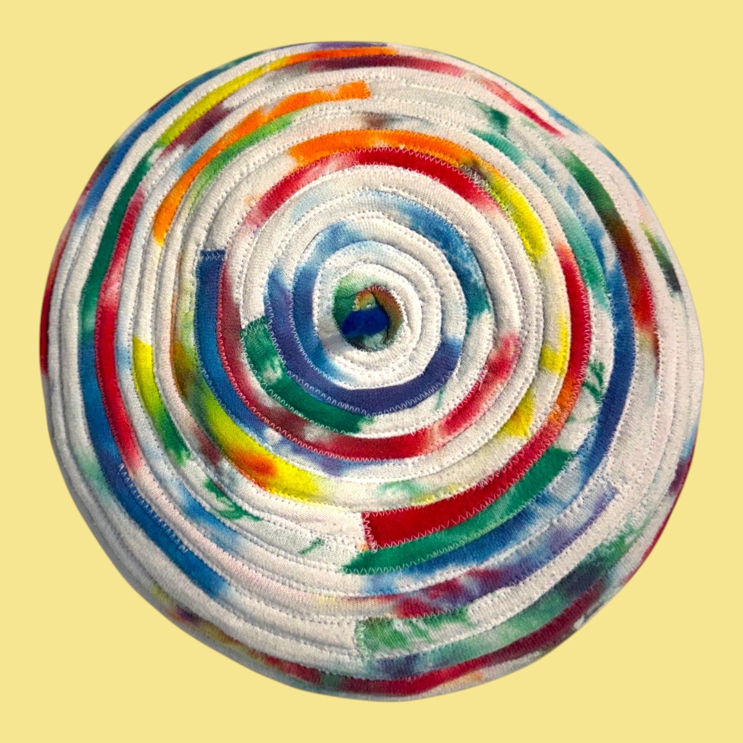 Blue Greenie beret made from coiled tie-dye t-shirt fabric strips in a vibrant multi-colored spiral pattern.